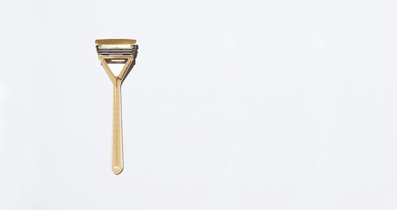 A gold razor on a plan white background.