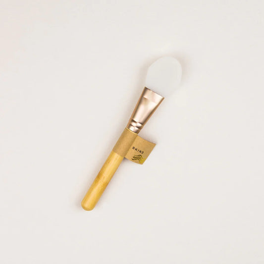 Image of a mask applicator with a wooden handle, metal middle, and white silicone top