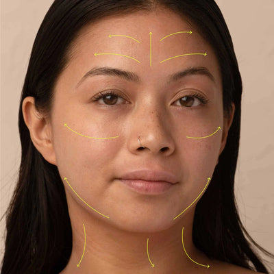 Photograph of model's face, arrows drawn over to showcase the direction of product application.