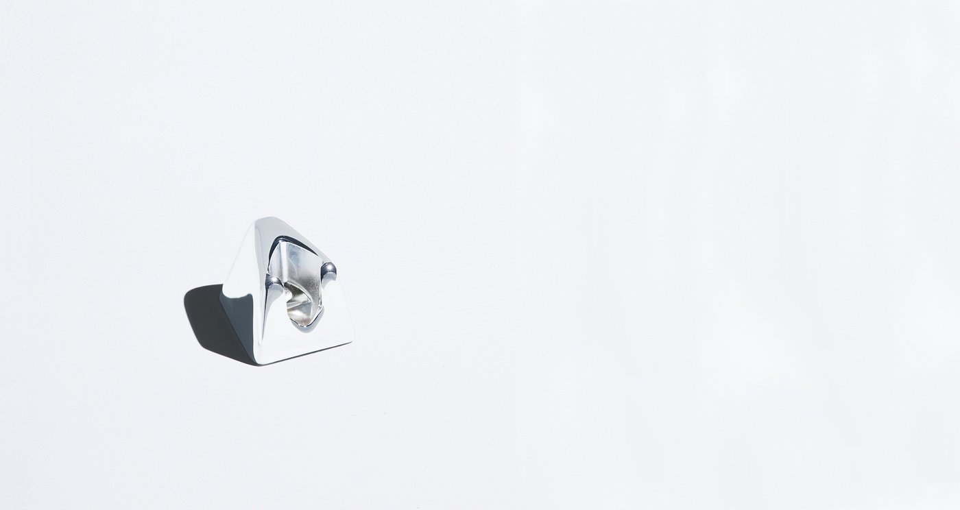 A chrome razor stand sits alone on a plain white background