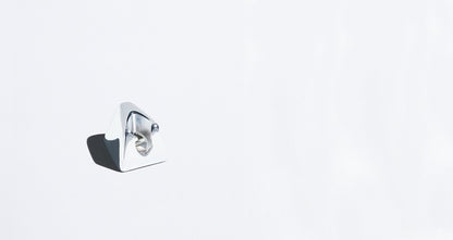 A chrome razor stand sits alone on a plain white background