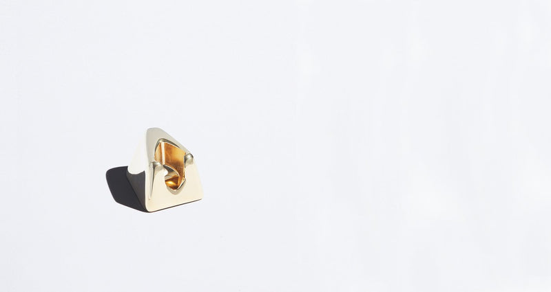 A gold razor stand sits alone on a plain white background